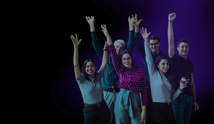A diverse group of six smiling young professionals enthusiastically raising their arms, standing against a dark purple background, symbolizing teamwork and positivity.