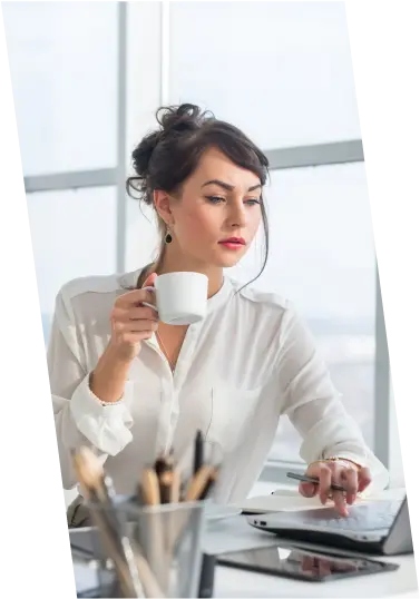 A young woman holding a coffee cup while attentively looking at her laptop, exploring job opportunities and preparing for her next career move.
