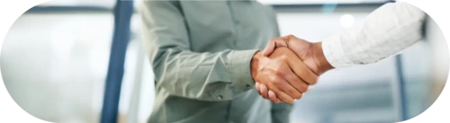 Close-up of a handshake between two individuals in a professional setting.